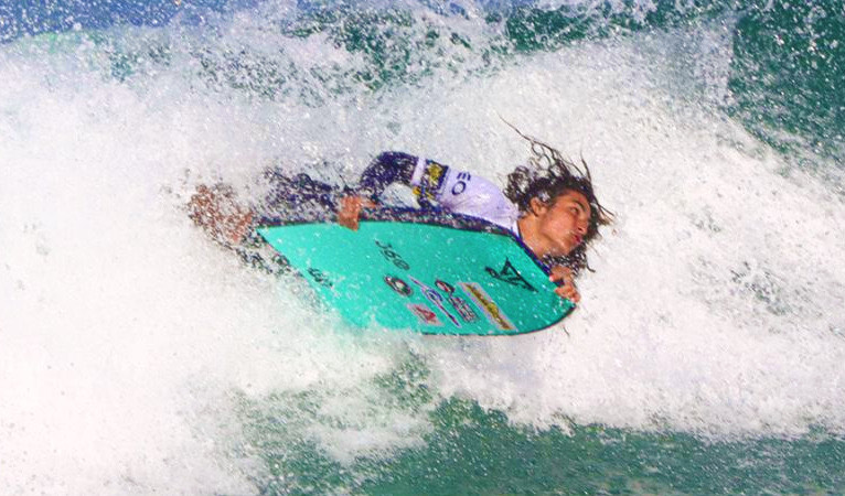 um rapaz pega onda em uma prancha de bodyboarding